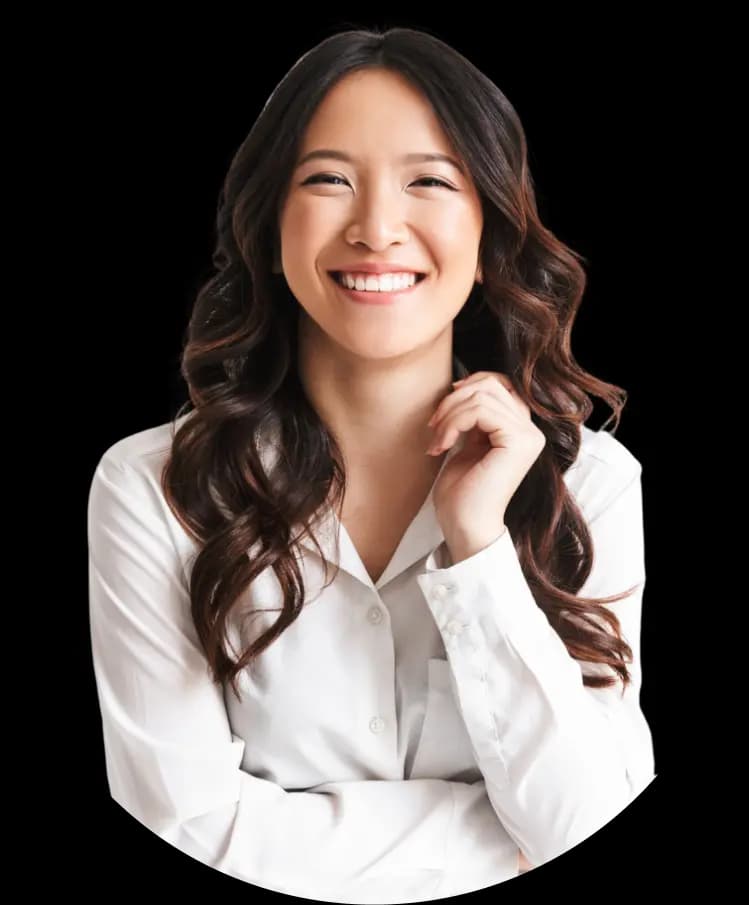 A young woman with light skin and long wavy dark hair, wearing a white blouse. She is smiling brightly and looking very cheerful.